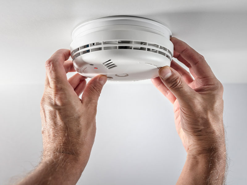 Byers Electric technician installing a smoke detector for home fire safety and code compliance