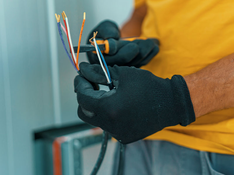 Byers Electric technician stripping multicolor electrical wires for a safe panel connection
