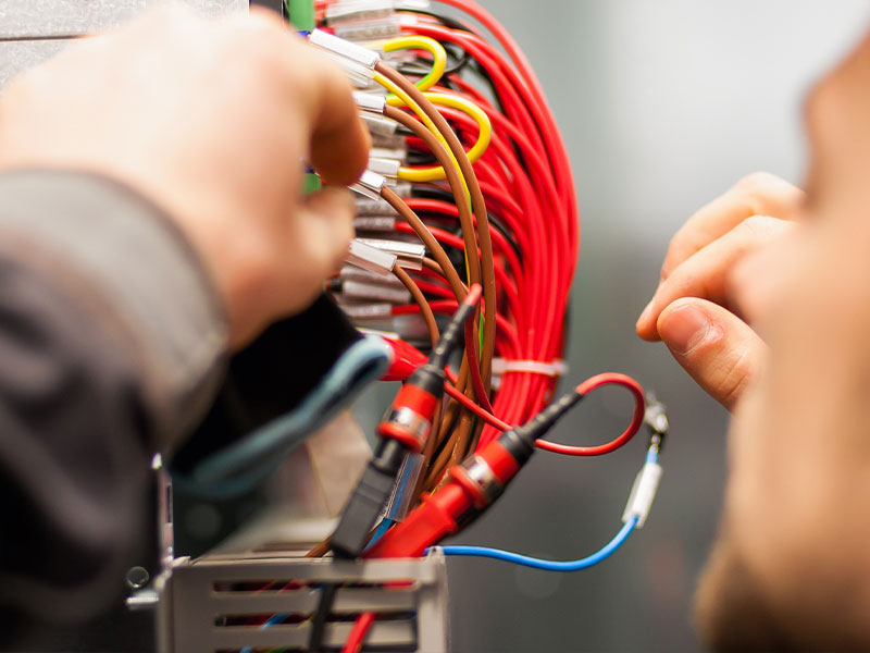 Byers Electric technician testing control panel wiring connections in a commercial electrical system