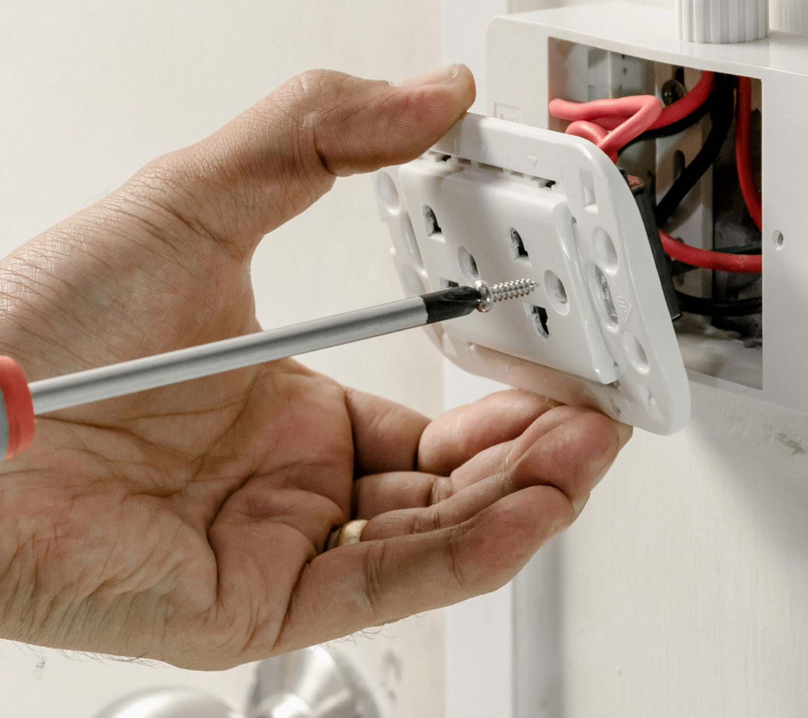 Byers Electric technician securing residential electrical outlet during safe wiring installation